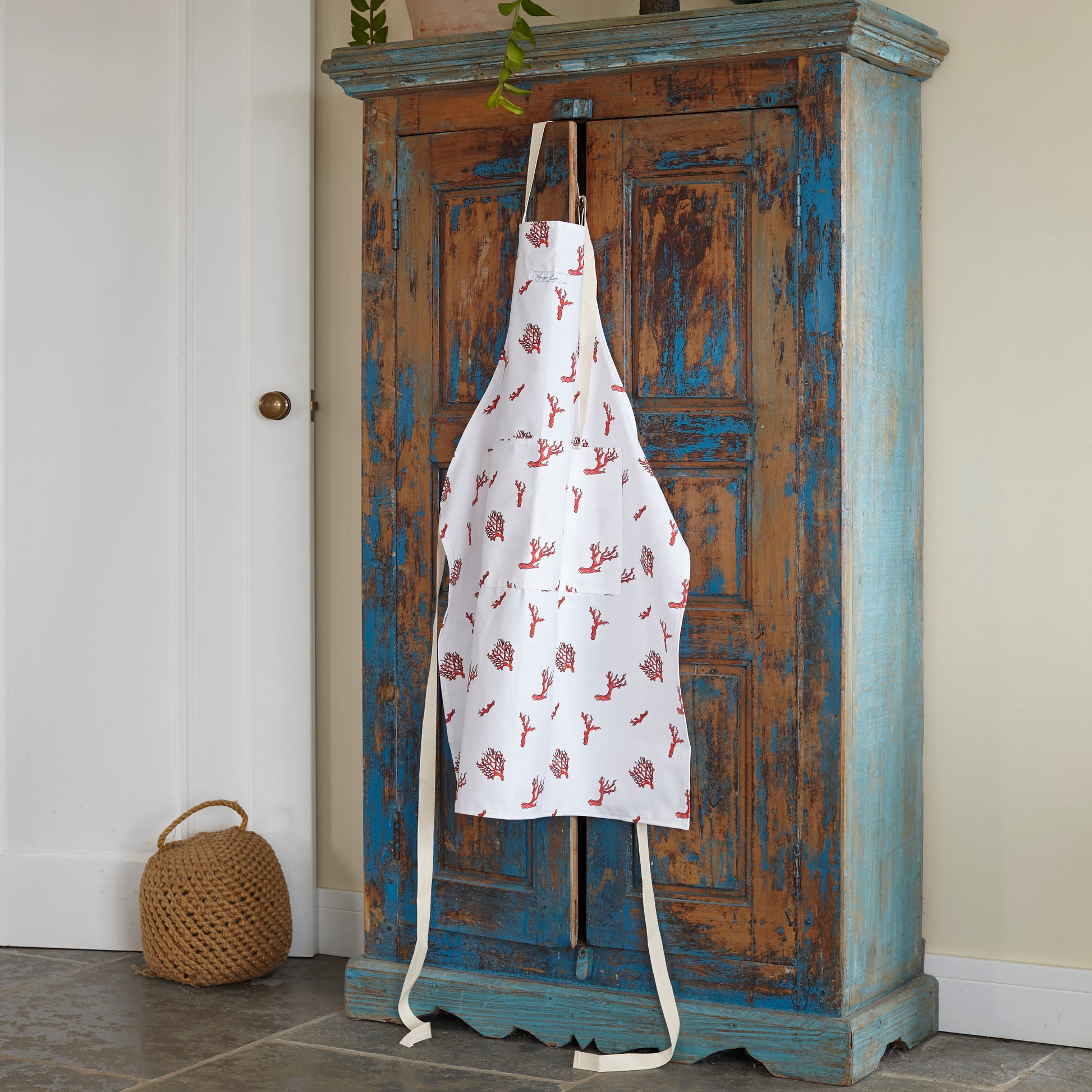 coral print apron hanging over cupboard in kitchen 
