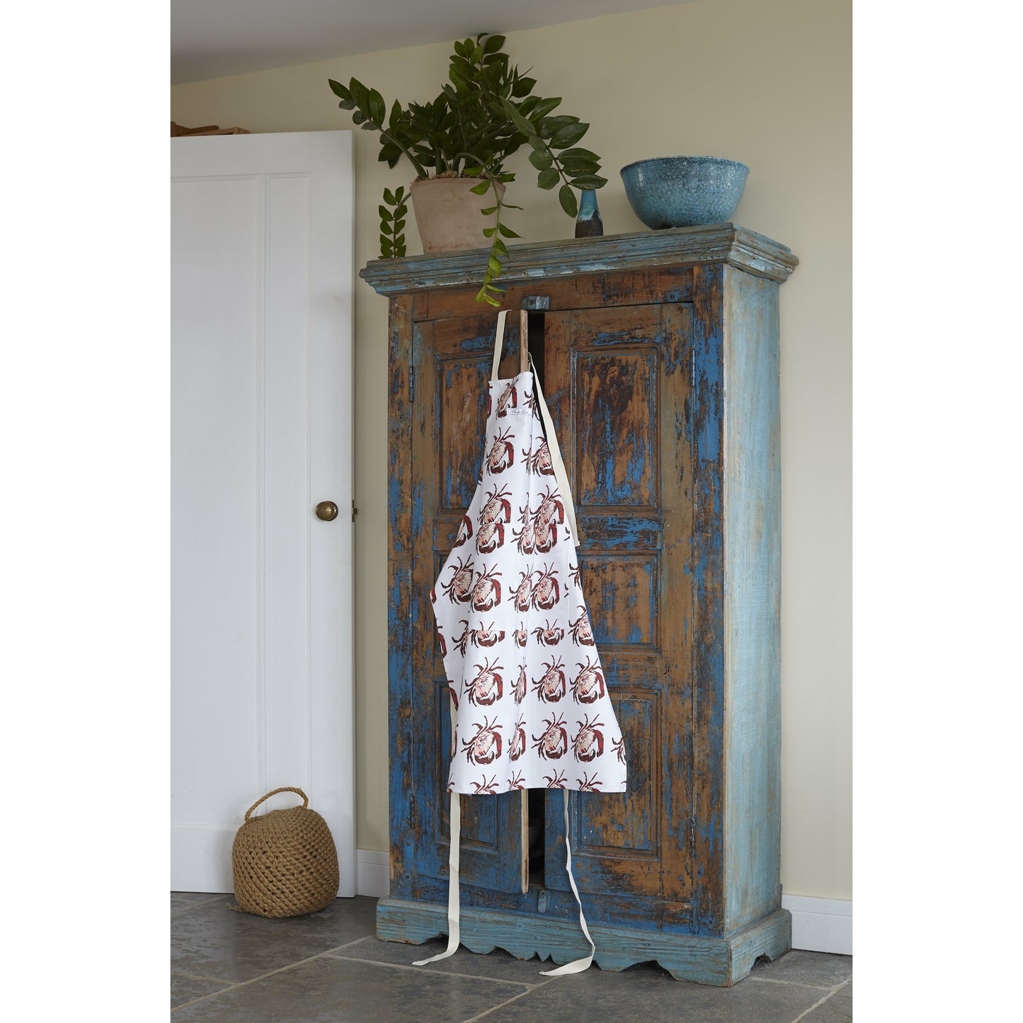 crab print apron hanging over a cupboard door 
