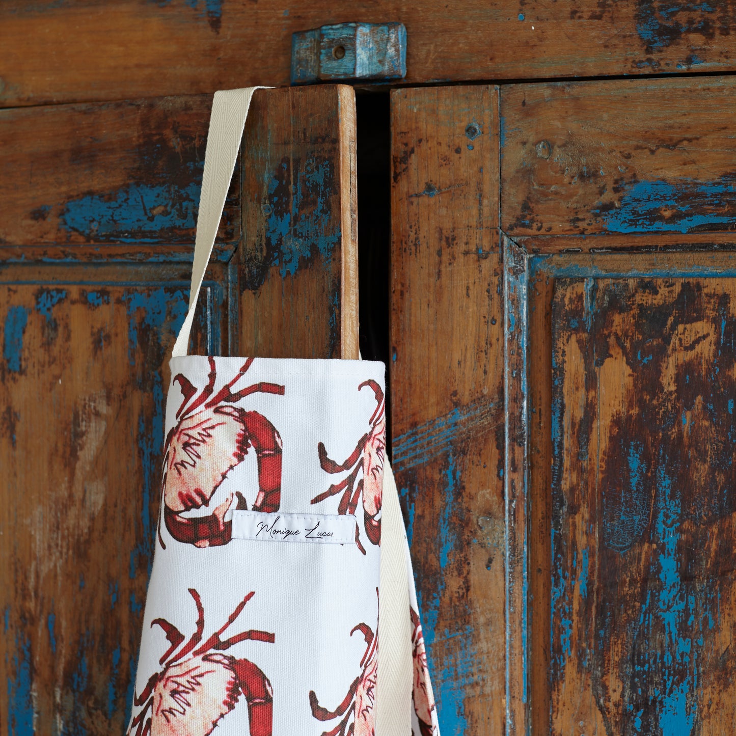 crab print apron hanging over cupboard door - close up 